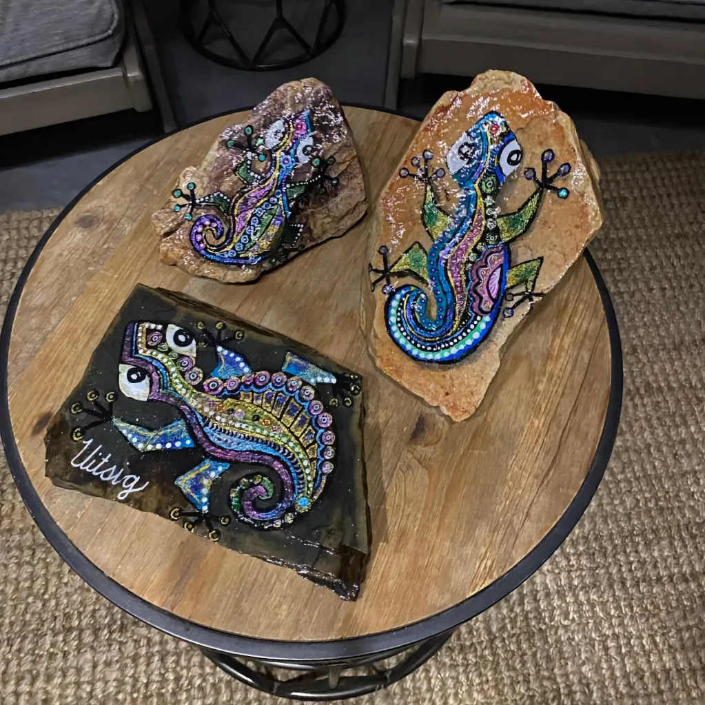 big gecko painted rock art pieces on a coffee table