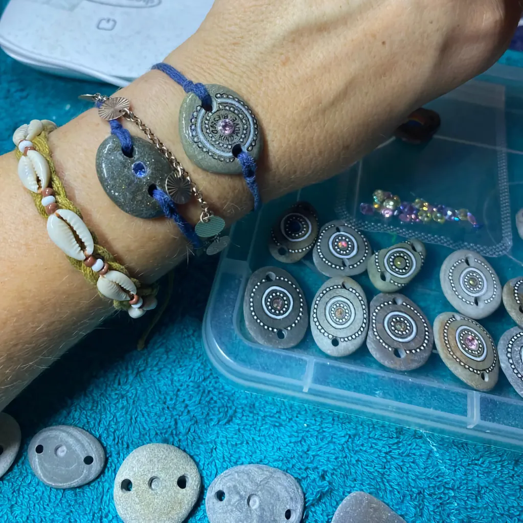 three bracelets on wrist with assortment of pebbles at various stages of production into Pocket Pebble bracelets