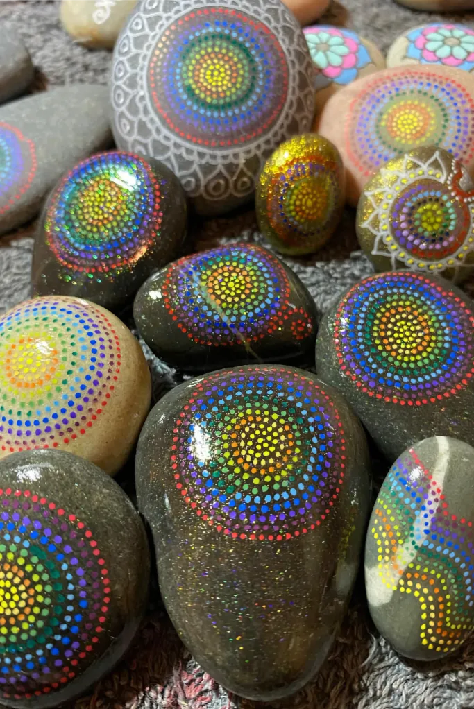selection of ornate hand-painted pebbles laid out on a grey towel
