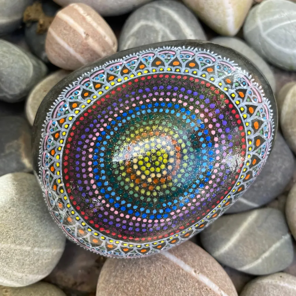 Single ornately painted stone resting on a bed of neutral coloured stones