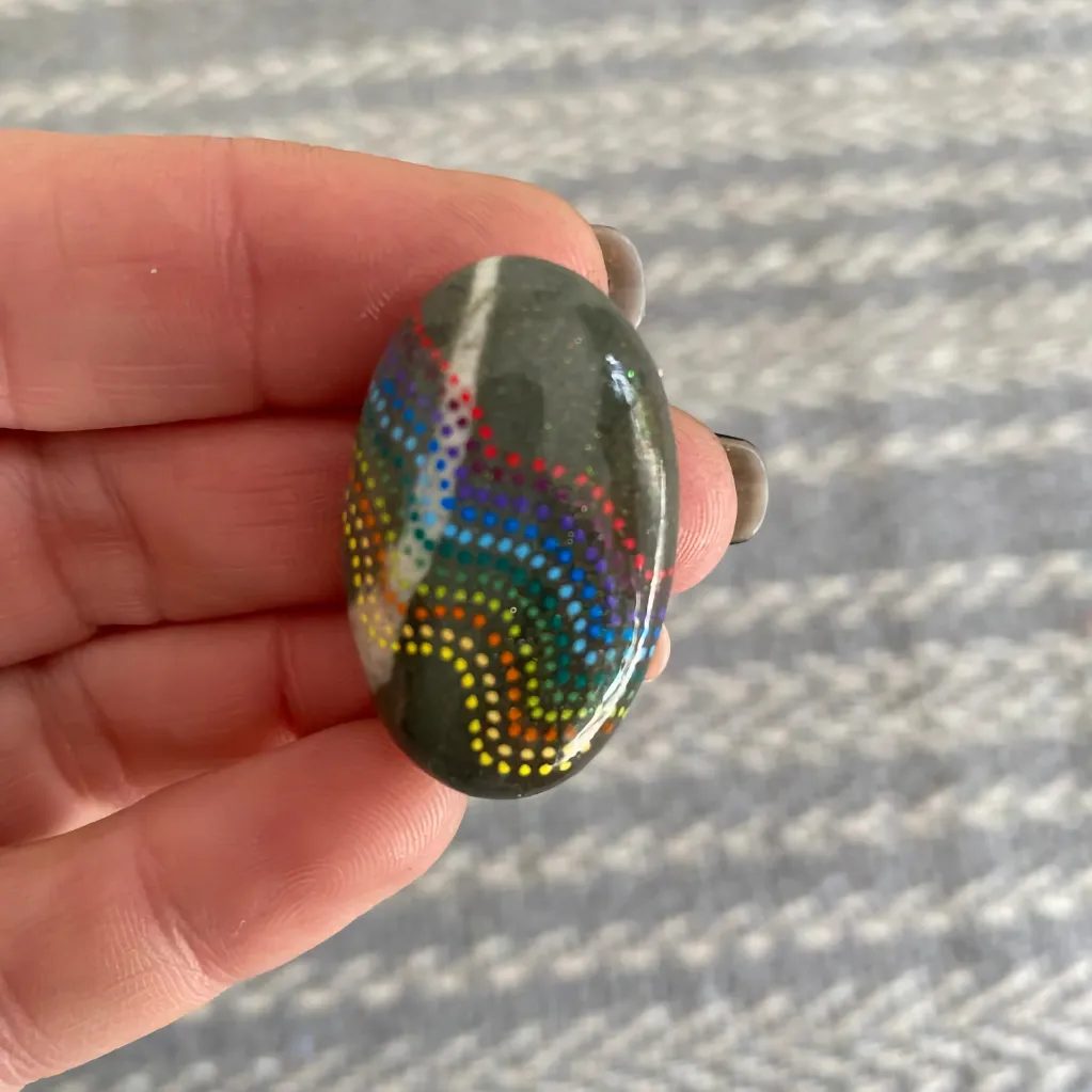 Beautiful tribal dotted pebble held on the fingertips of a lady's hand