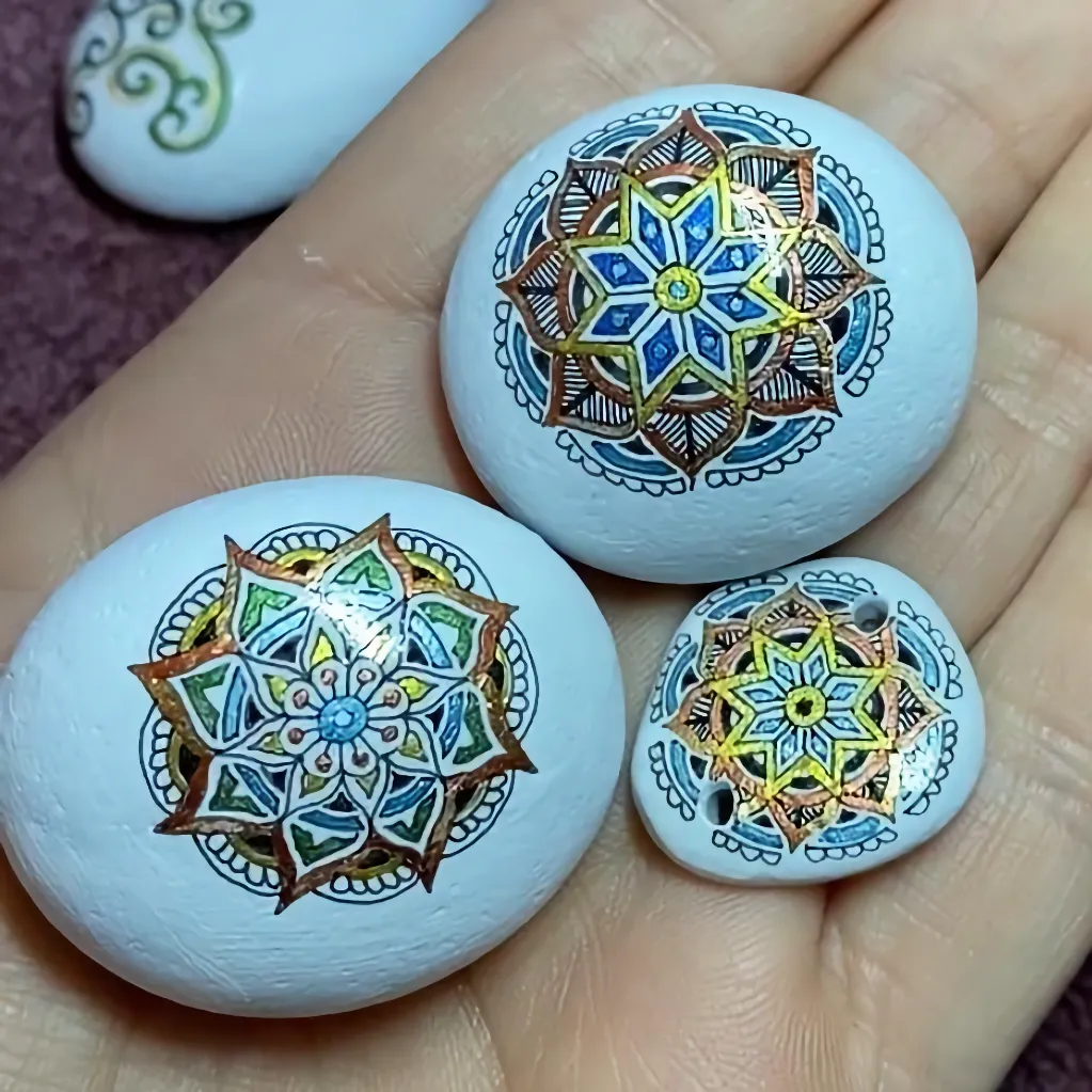 three mandala painted pebbles in the palm of a hand